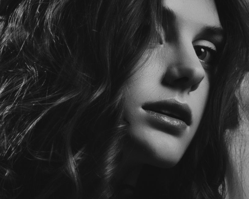 Stylish black and white portrait capturing a woman with expressive eyes and curly hair.