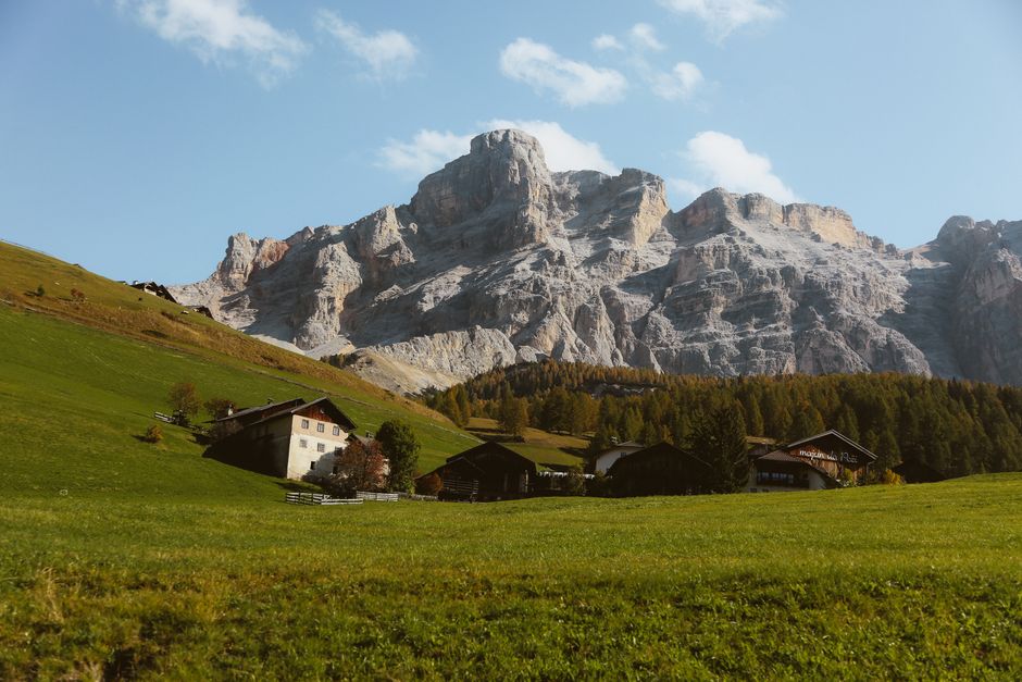 Beautiful mountainous landscape in the Dolomites featuring green meadows and rustic village homes.