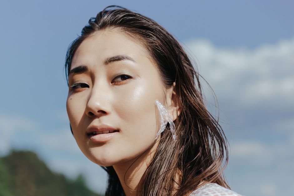 Close-up of a woman with windswept hair and plastic on her face against a clear sky.