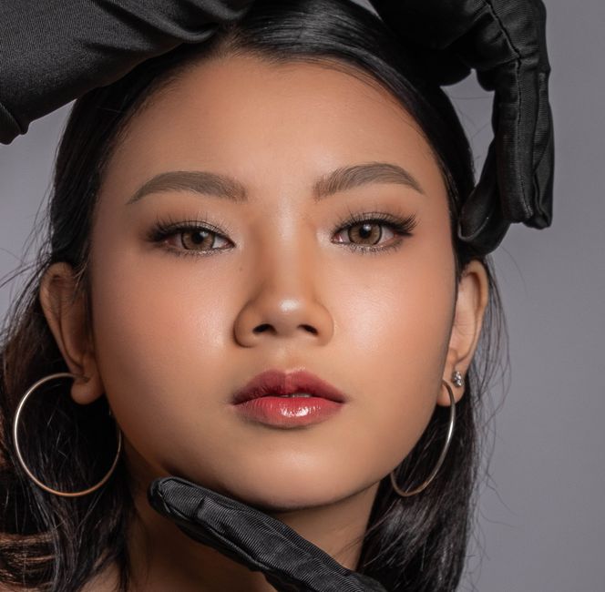 Close-up portrait of a young woman accentuating elegance and beauty with black gloves.