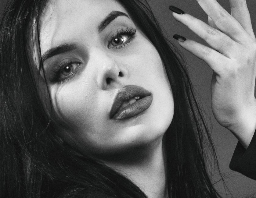 Close-up black and white portrait of a woman with expressive eyes and dark manicure.