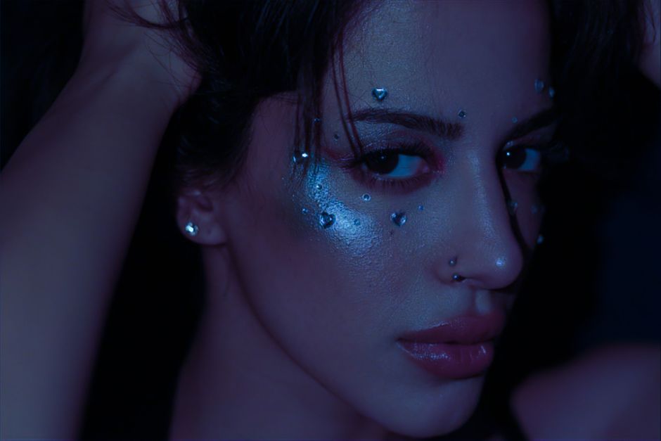 An artistic close-up portrait of a woman adorned with glitter and gems, emphasizing beauty and creativity.