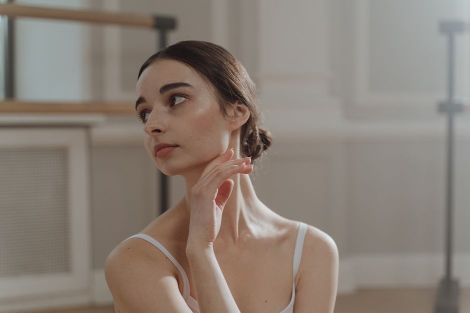 Graceful ballerina posing in a soft-lit dance studio, showcasing elegance and beauty.