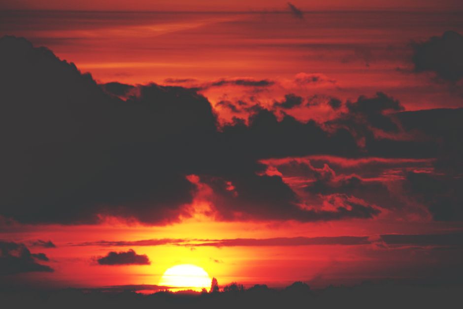 A breathtaking view of a dramatic red sunset with silhouetted clouds creating a moody atmosphere.