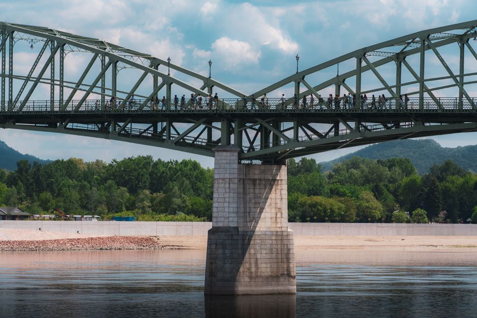 Crowds walking on the Esztergom bridge over the Danube with scenic landscape views.