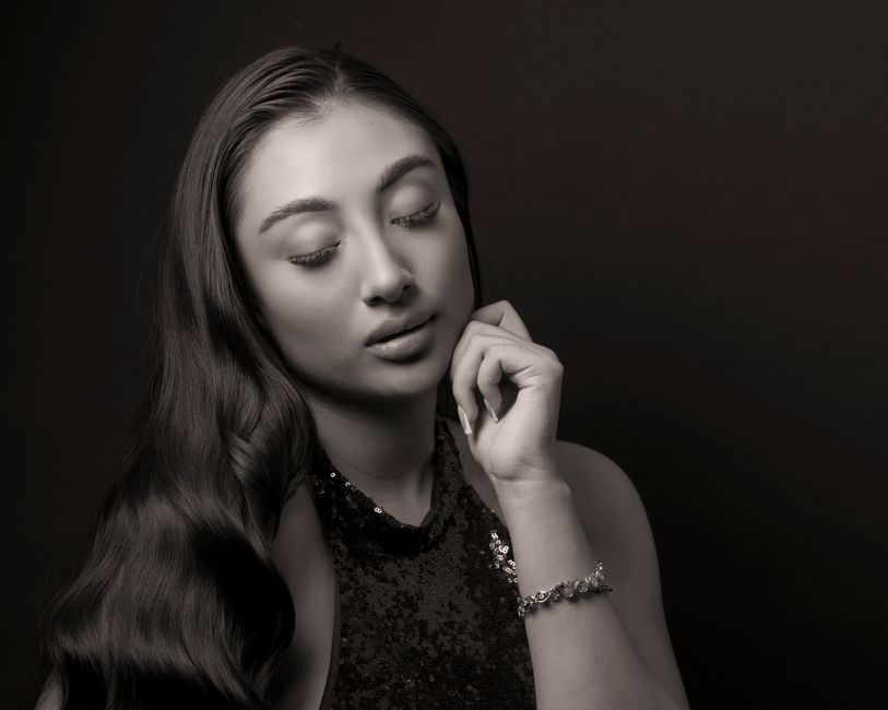 Black and white portrait of a woman with long hair and sequined dress, eyes closed.