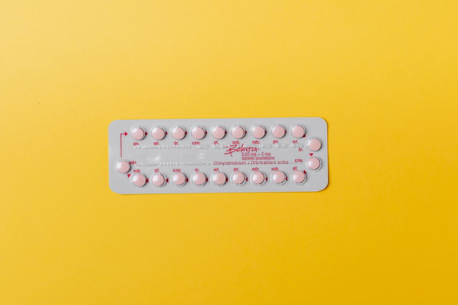 Close-up of a blister pack of pink pills on a vivid yellow background for medication concept.